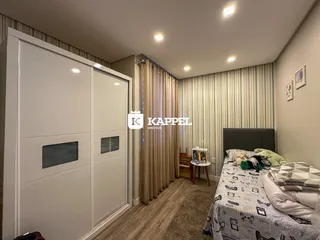 Quarto com cama e armários brancos e piso de madeira.