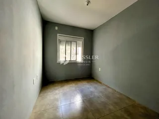 Vista interna de um corredor com paredes cinzentas e piso de cerâmica.