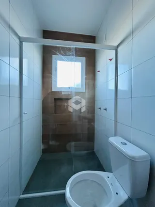Foto de um banheiro com revestimento cerâmico e vaso sanitário branco.