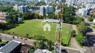 Vista aérea de um campo gramado cercado por árvores e construções residenciais.