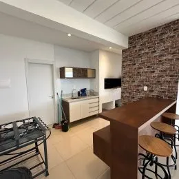 Vista interna de uma cozinha com bancada e armários claros.