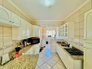 Foto de uma cozinha com armários brancos e bancadas de granito.