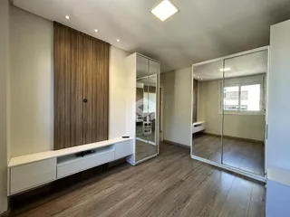 Ambiente interno de uma sala com piso de madeira e espelho refletindo o ambiente.