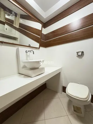 Foto de um banheiro com bancada branca e piso claro.
