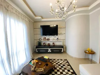 Sala de estar com grandes janelas e cortinas brancas.