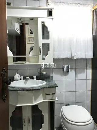 Foto de um banheiro com azulejos brancos e bancada.