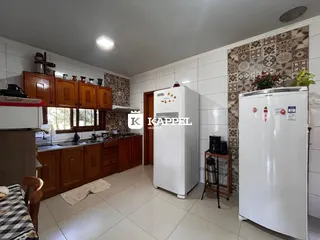 Cozinha com armários de madeira e piso de cerâmica em uma residência.