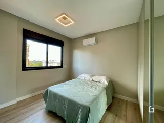 Quarto com janela e cama de casal em ambiente claro.