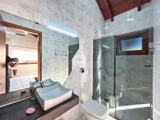 Foto de um banheiro com azulejos brancos e box de vidro.