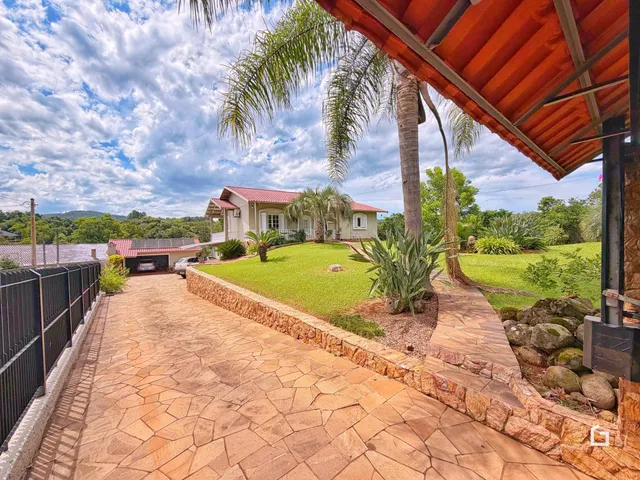 Fachada de casa com jardim e calçada de pedras.
