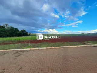 Vista externa de um campo verde e paisagem sob um céu parcialmente nublado.