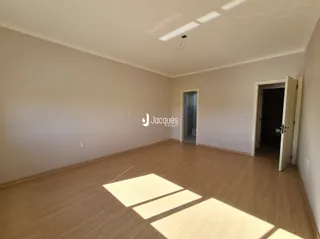Interior de uma sala com piso de madeira e paredes brancas.