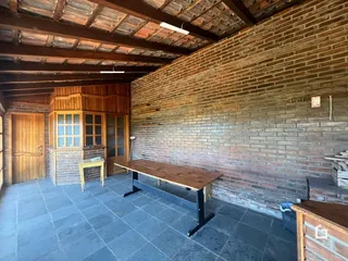 Imagem de uma área interna com parede de tijolos aparentes e teto de madeira.