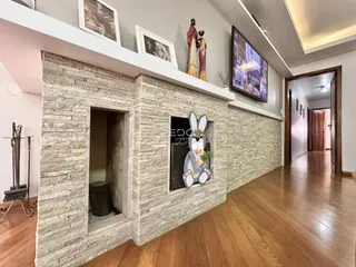 Uma parede de pedra revestida com tijolos delimita uma área interna da residência.