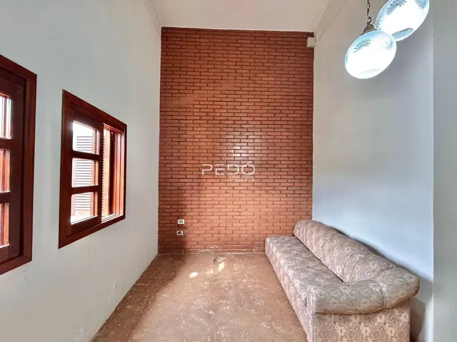 Hall de entrada com parede de tijolos aparentes e janelas de madeira.
