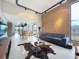 Uma sala de estar ampla com piso de cerâmica e parede de tijolos expostos.