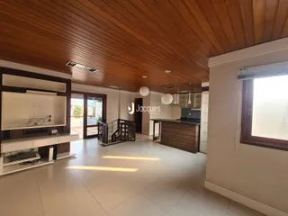 Interior de uma sala de estar com teto de madeira e piso de cerâmica.