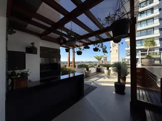 Varanda com estrutura de pergolado e vista panorâmica da cidade.
