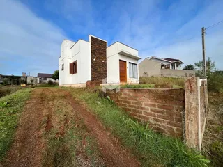 Vista externa de uma residência com fachada branca e detalhes em tijolo.