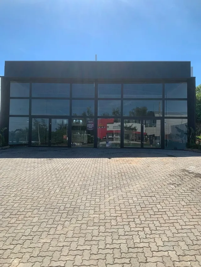 Fachada moderna de um edifício com grandes painéis de vidro e revestimento de tijolos.