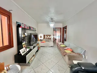 Sala de estar com sofá e televisão em um ambiente claro com piso de cerâmica.