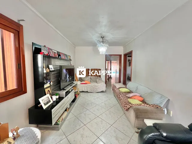 Sala de estar com sofá e televisão em um ambiente claro com piso de cerâmica.