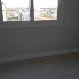 Foto de uma parede interna com uma janela mostrando a paisagem urbana.