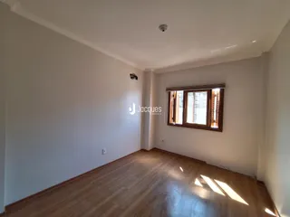 Ambiente interno de uma sala com piso de madeira e grande janela.