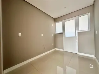 Vista interna de um corredor com piso de cerâmica claro.