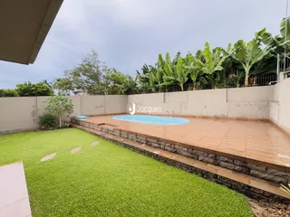 Vista externa de um quintal com piscina e gramado.