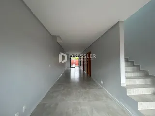 Vista de um corredor interno de uma residência com paredes cinzas e piso de concreto.