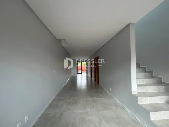Vista de um corredor interno de uma residência com paredes cinzas e piso de concreto.