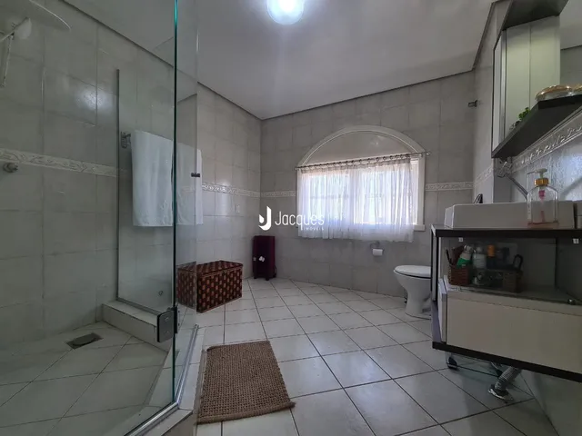 Interior de um banheiro com piso de cerâmica e box de vidro.