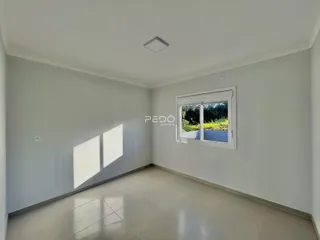Ambiente interno de uma sala com piso de cerâmica e paredes brancas.