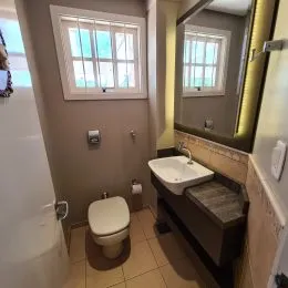 Foto de um banheiro interno mostrando um vaso sanitário e uma pia com piso de cerâmica.