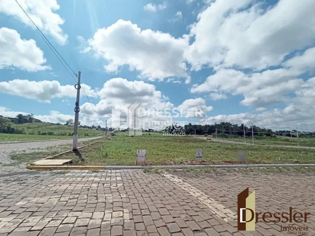 Vista externa de uma propriedade com gramado e área pavimentada.