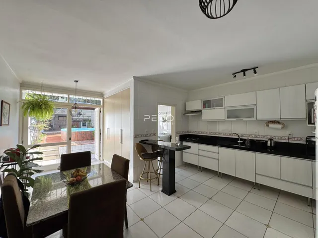 Ambiente de sala de jantar e cozinha com portas de vidro abrindo para o exterior.