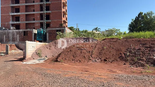 A foto mostra uma construção em andamento com terra exposta no primeiro plano.