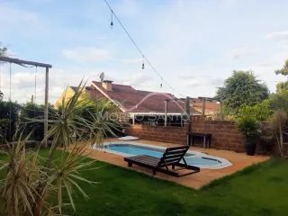 Foto da área externa com piscina e jardim.