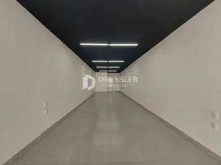Hall de corredor longo com paredes brancas e piso claro.