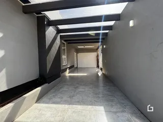 Corredor interno com piso de concreto e teto de claraboia.
