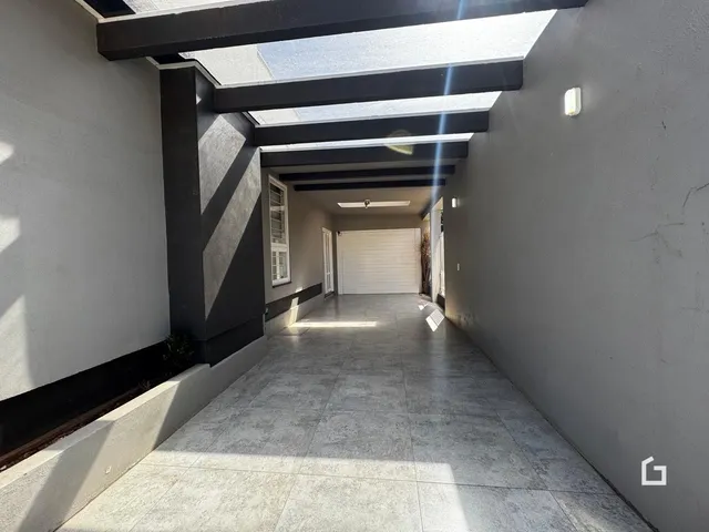 Corredor interno com piso de concreto e teto de claraboia.