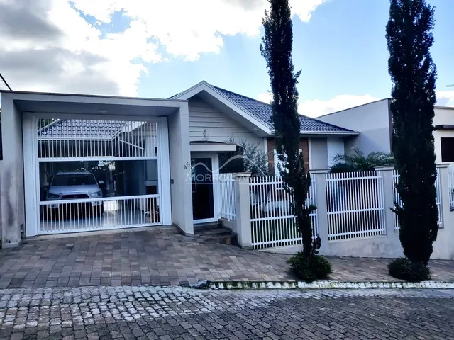 Fachada de uma residência em Lajeado, Brasil, com portão e muro branco.