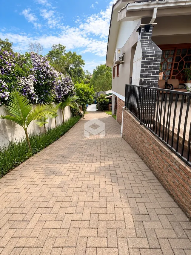 Vista da fachada de uma propriedade com calçada de tijolos e vegetação.