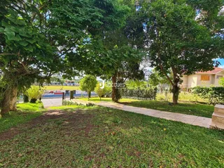 Vista externa de um jardim com árvores e gramado verde.