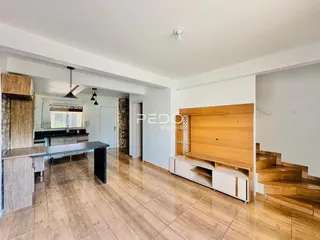 Ambiente interno de uma sala com piso de madeira clara e móveis de madeira.