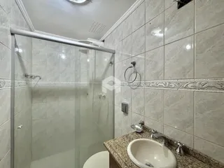 Foto de um banheiro com revestimento de cerâmica e box de vidro.