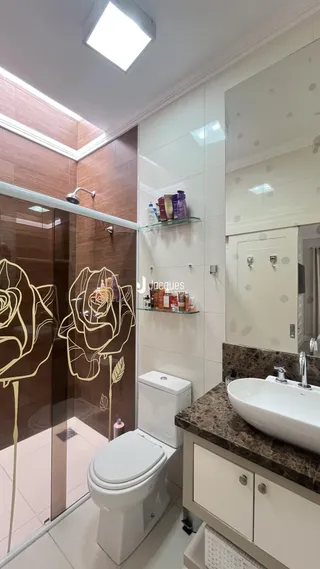 Banheiro moderno com box de vidro e louças brancas.