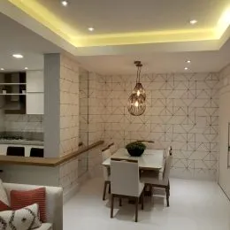 Corredor interno com parede texturizada e iluminação embutida no teto.