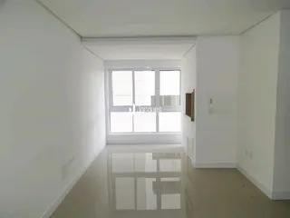 Interior de um ambiente claro com paredes brancas e piso reflexivo.